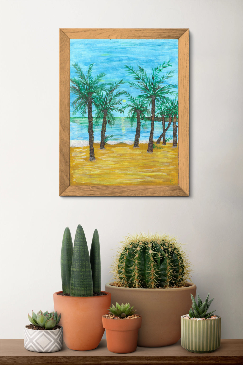 Framed painting of a beach scene with palm trees on a wall above a shelf for coastal home decor style.

